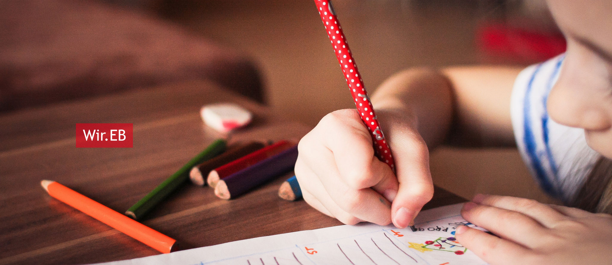 Kind malt mit Stiften auf Papier
